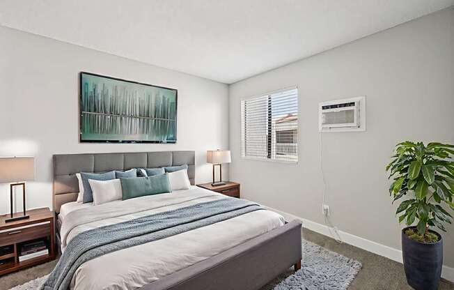 A bedroom with a bed, nightstands, and a plant.