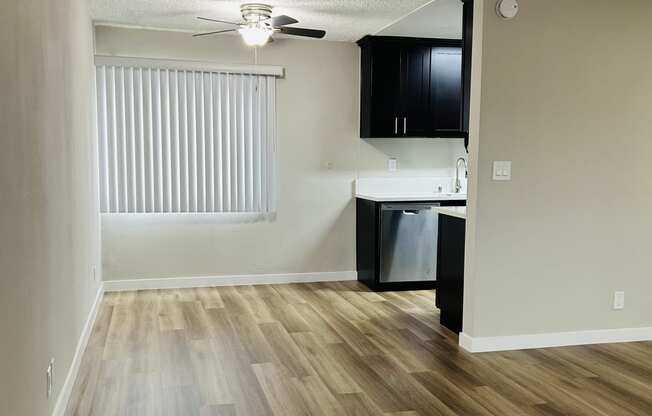 an empty living room and kitchen with wood flooring and a ceiling fan