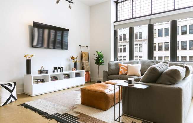 a living room with a large window and a tv on the wall at The Ferguson Apartments, Detroit, 48226