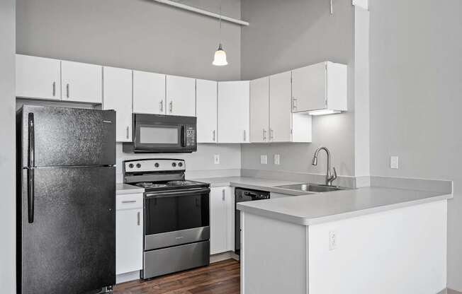 A modern kitchen with a black refrigerator, stove, and microwave.