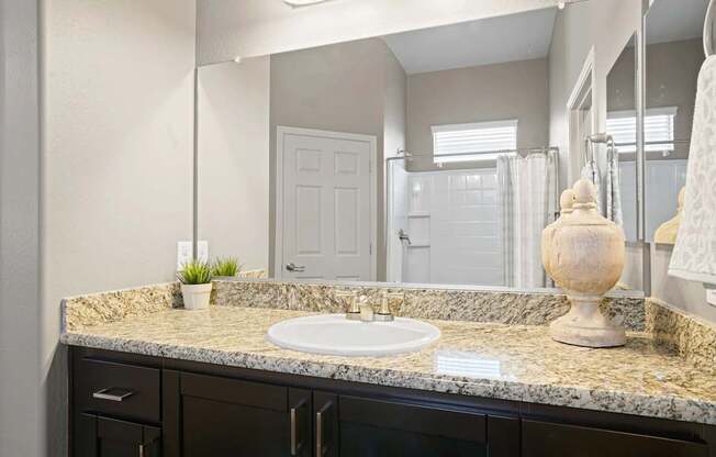 A bathroom with a granite countertop and a white sink.