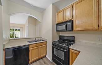 a kitchen with wooden cabinets and black appliances at The Village Apartments, Van Nuys, 91406