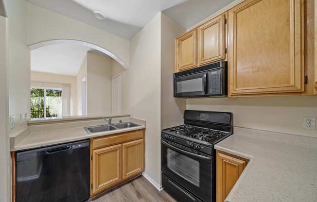 a kitchen with wooden cabinets and black appliances at The Village Apartments, Van Nuys, 91406