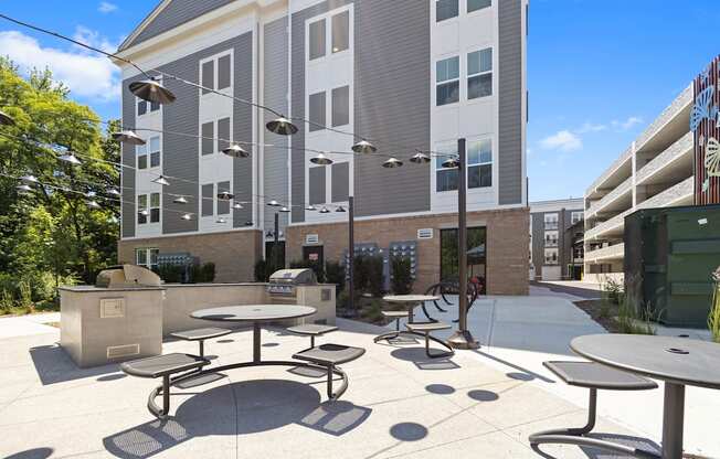 a patio with tables and chairs in front of an apartment building