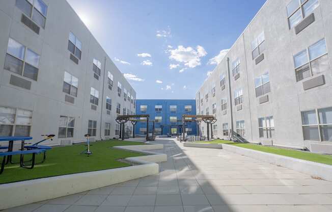 an exterior view of an apartment building with grass and benches