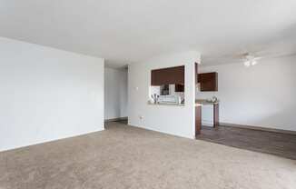 an empty living room with white walls and a kitchen