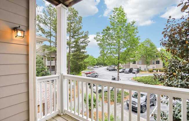A view from a balcony overlooking a street with cars and trees.