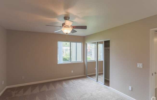 an empty living room with a ceiling fan and a window