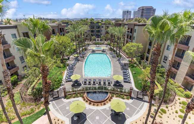 A pool surrounded by palm trees and umbrellas at The Kitt at Warner Center Apartments, Woodland Hills 91303