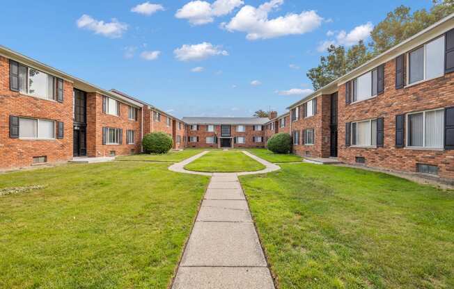 an exterior view of an apartment building with a grass yard and sidewalk