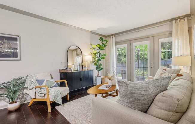 A living room with a couch, chair, and potted plant.