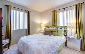 a bedroom with a bed and two windows with curtains