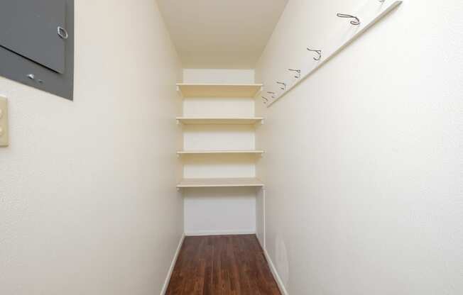 a corridor with white walls and shelves and a wood floor. Fargo, ND Country Club Apartments.