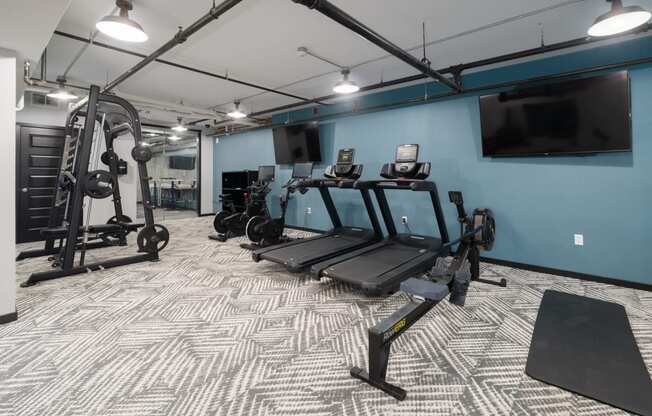 a spacious fitness room with cardio equipment and a flat screen tv