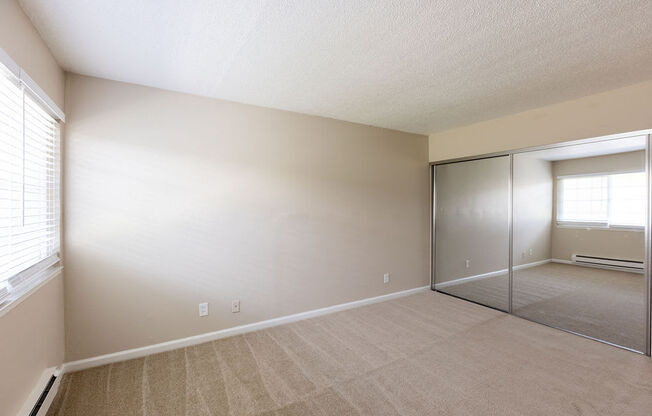 an empty living room with a mirrored closet door