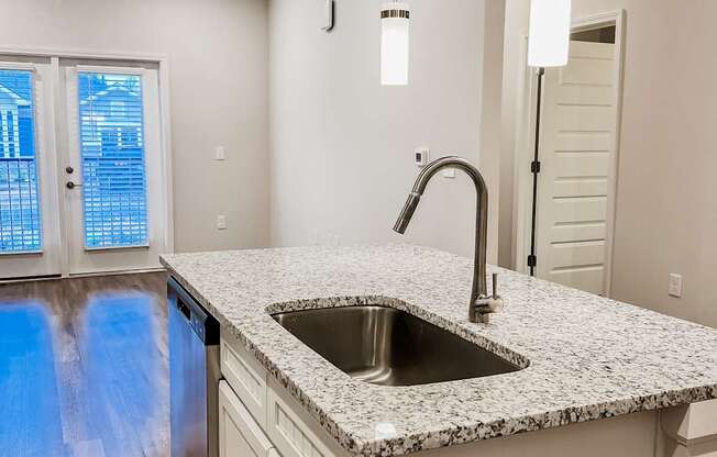 A kitchen with a granite countertop and a stainless steel sink.