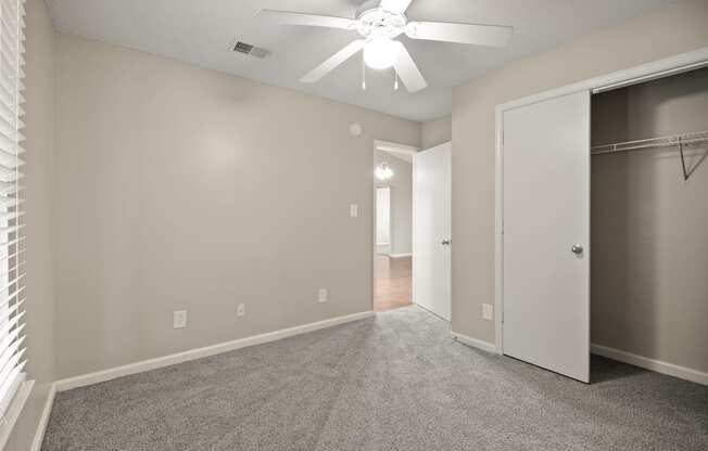 A room with a ceiling fan and a closet.