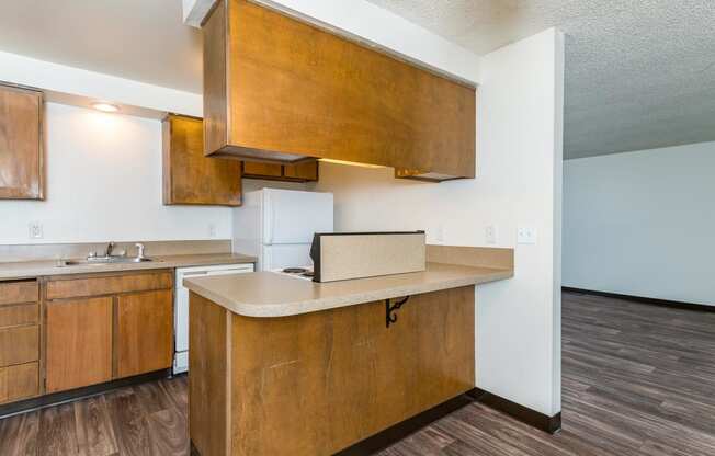 Pinewood Terrace Apartments | View of kitchen from dining room. Maple colored cabinetry with counter space for stools.