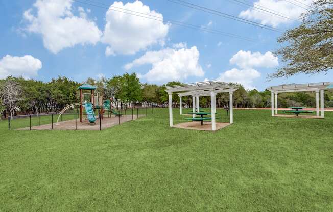 A playground with a green slide and white pergola.