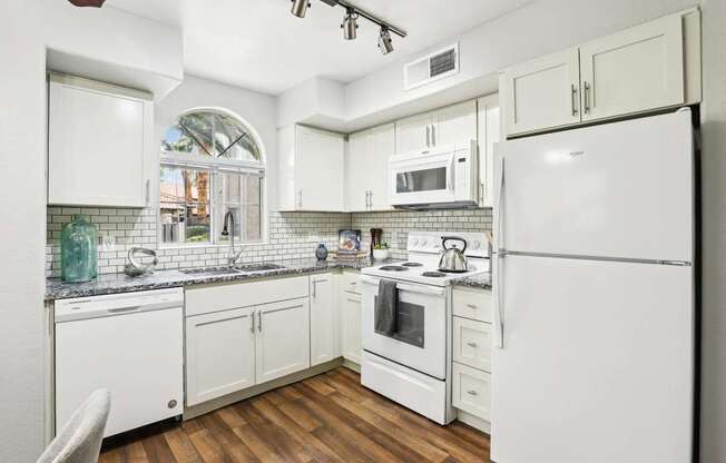 A kitchen with white appliances and cabinets.