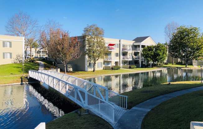 a white bridge over a pond with apartment buildings in the background