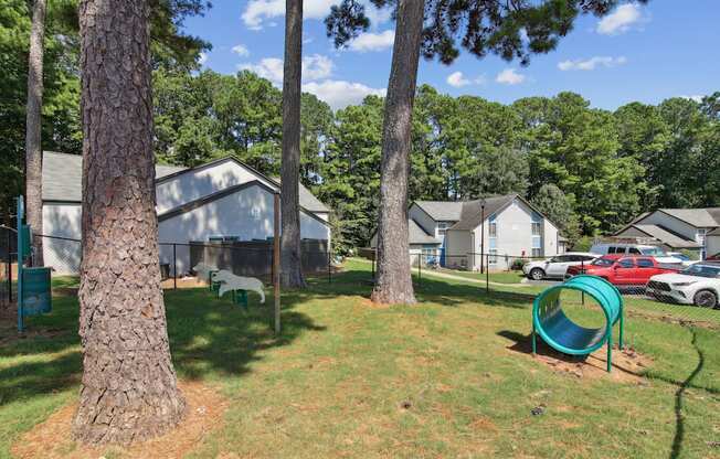 A playground with a green slide and a white dog in the background.