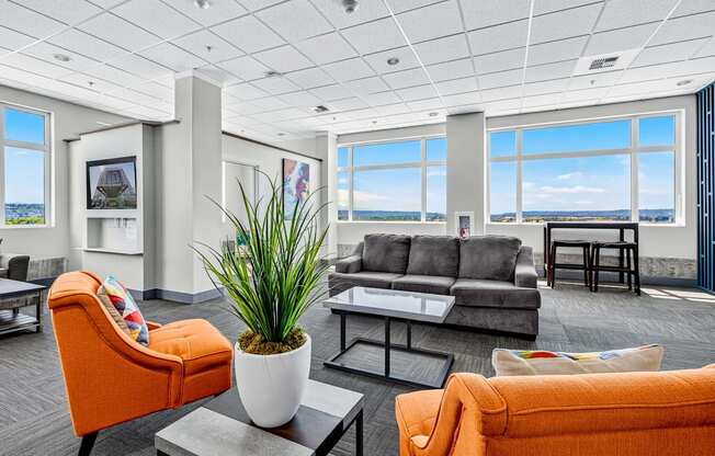 A bright orange chair sits in a spacious room with a large window overlooking the water.