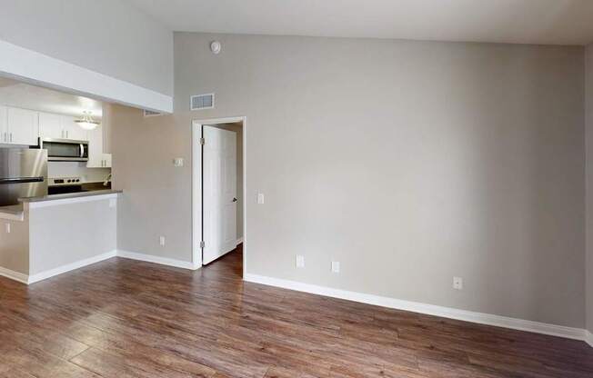 A kitchen with a refrigerator, microwave, oven, and cabinets is visible through an open door.