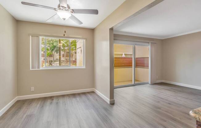 A room with a ceiling fan and sliding glass doors.