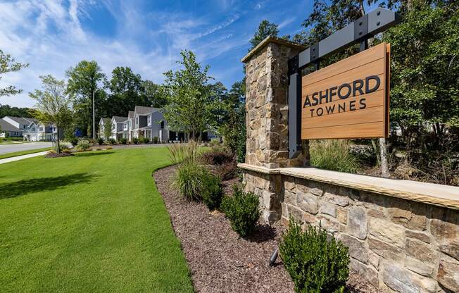 a sign for ashford towers on the side of a stone wall with a lawn