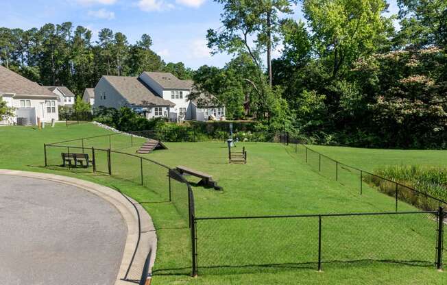 a park with a fenced in area and houses in the background