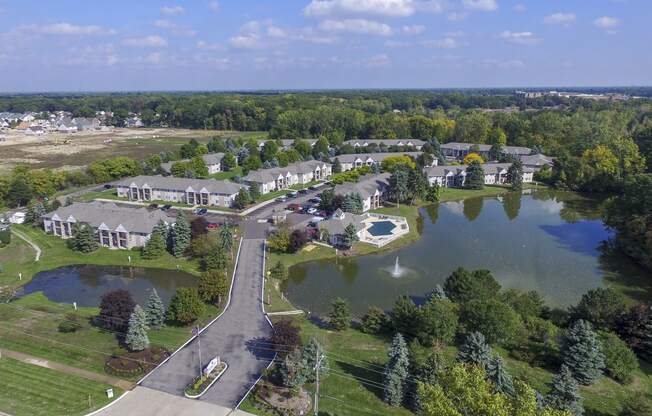 an aerial view of a community with a pond and trees