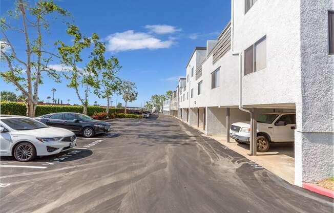 a parking lot in front of a white apartment building