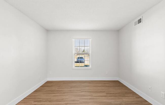 A room with a window and wooden flooring.
