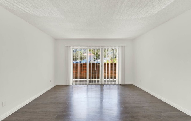 an empty living room with a sliding glass door to a balcony at Willow Tree Apartments, Torrance, CA