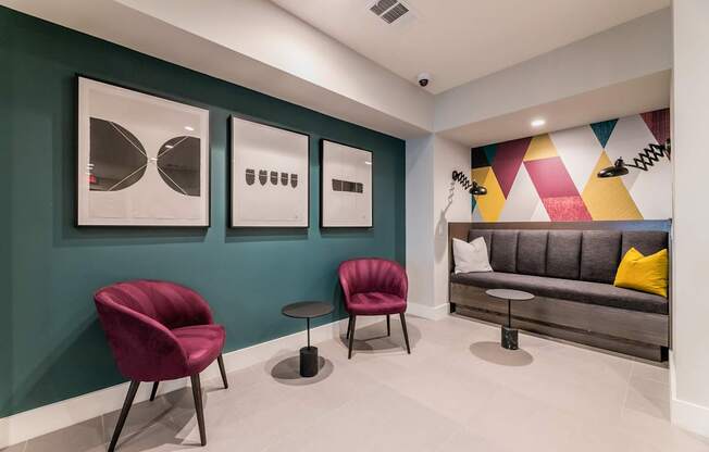 A living room with a grey sofa, two red chairs and a small table.