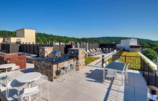 a rooftop patio with tables and chairs and a building in the background