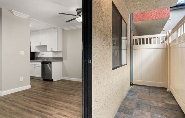 A kitchen with white cabinets and a black fridge is visible through a doorway.