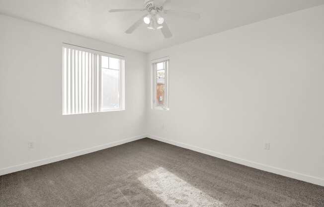 an empty room with carpet and a ceiling fan