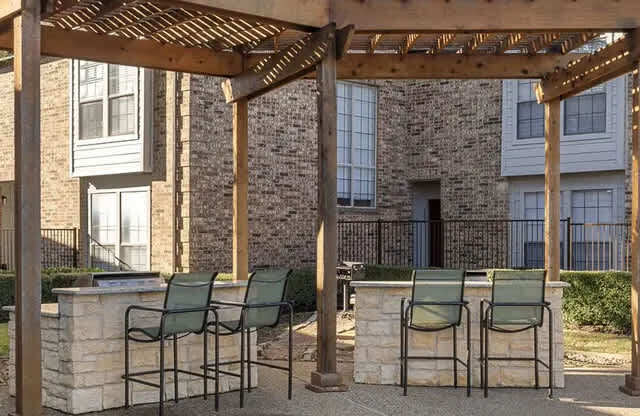 A pool area with a pergola and chairs.