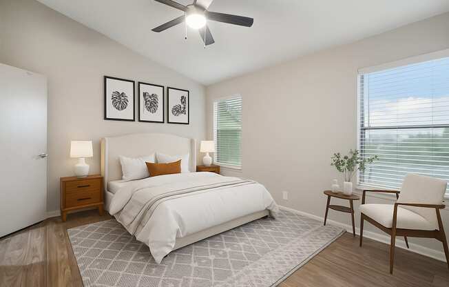 A bedroom with a large bed, a ceiling fan, and a chair.
