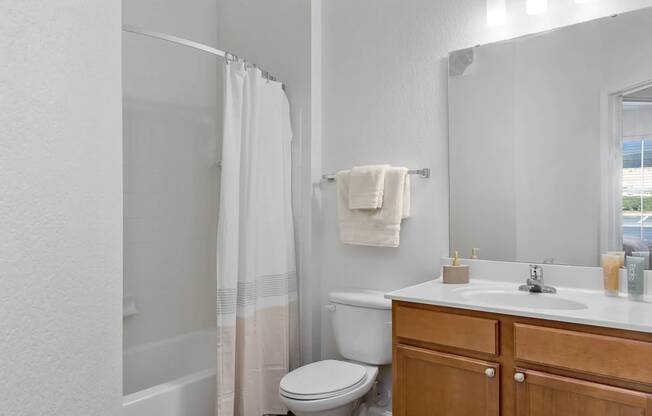 A white bathroom with a toilet, sink, and shower.