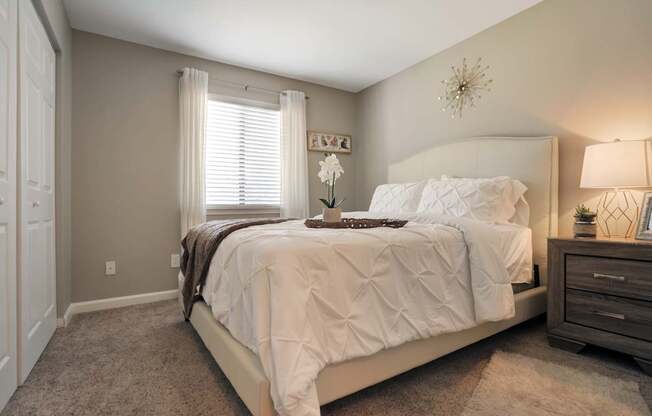 A bedroom with a large bed and a nightstand with a lamp.