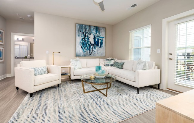 a living room with white couches and chairs and a rug