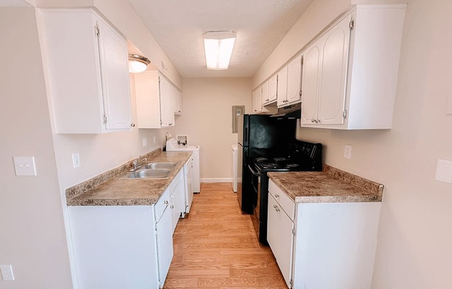 an empty kitchen with white cabinets and a black stove