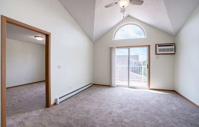 A room with a ceiling fan and a window with a view of a fence and a house. Bismarck, ND Sierra Ridge Apartments