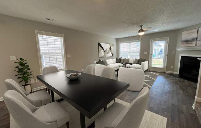 a living room and dining room with white chairs and a black table