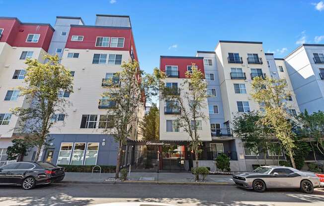 Property building on a city street with cars parked in front of it at Promenade at the Park Apartment Homes, WA 98125