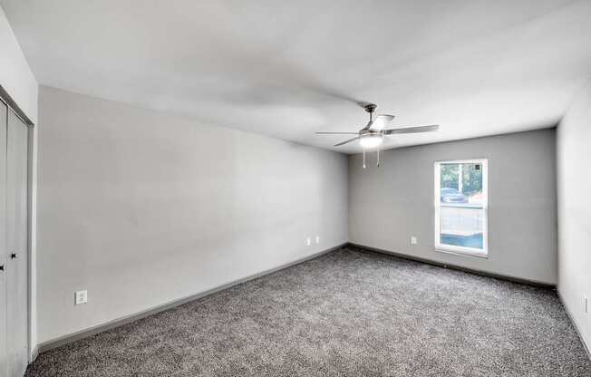 A room with a ceiling fan and a window showing a body of water.