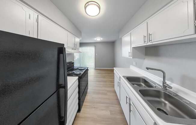 an empty kitchen with black appliances and white cabinets